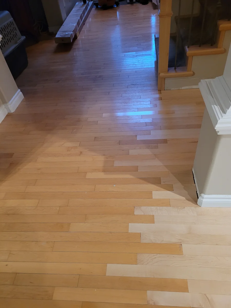 Hallway entryway where new prefinished hardwood integrates into the home's existing flooring near the staircase